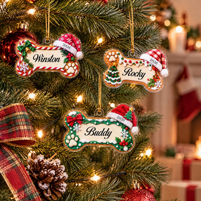 Personalized acrylic ornament dog name bone, three ornaments on a lit tree with plaid ribbon, pinecone and gifts