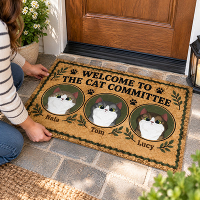 Personalized Cat Committee Doormat with three cat portraits being set down on stone steps by a person kneeling