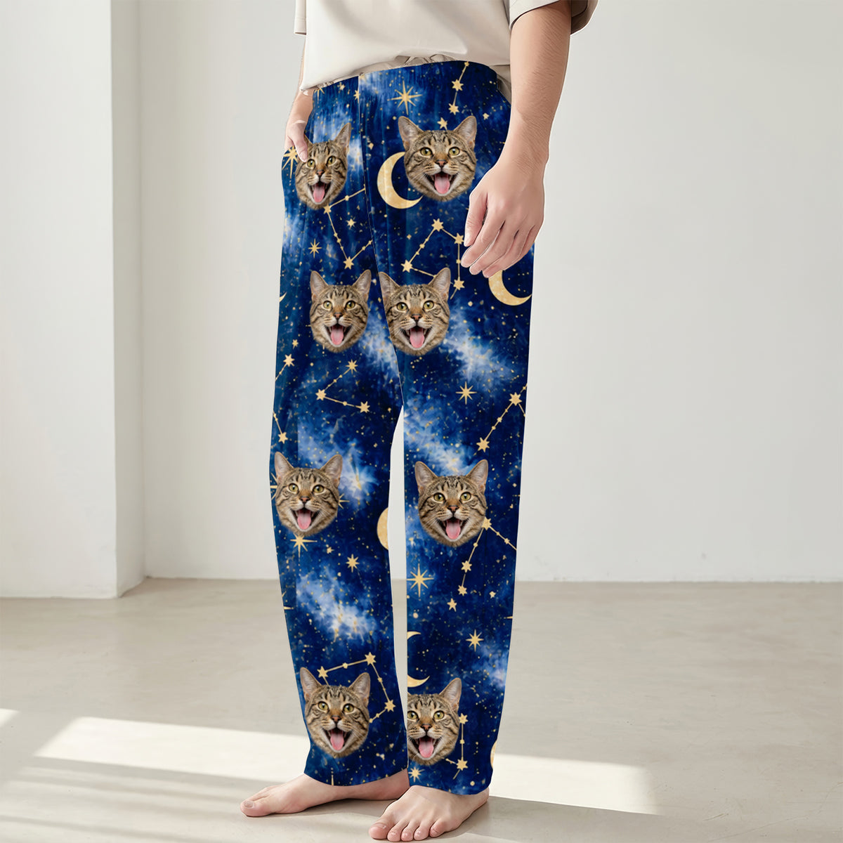 Custom pet photo personalized pajama pants worn by a person standing barefoot, cat faces on starry blue print