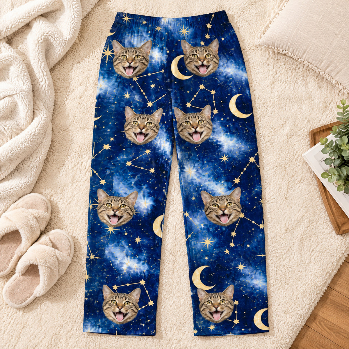 Custom pet photo personalized pajama pants laid flat on a cream rug beside fuzzy slippers and a soft blanket