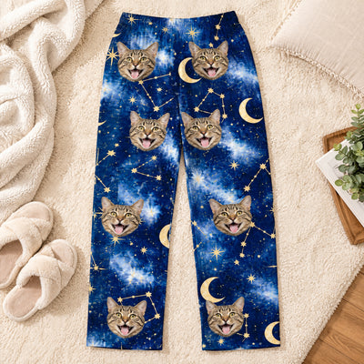 Custom pet photo personalized pajama pants laid flat on a cream rug beside fuzzy slippers and a soft blanket